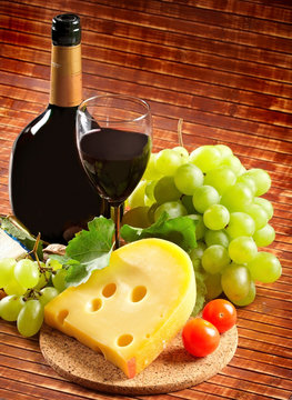 Red wine in fine glass with cheese and grape
