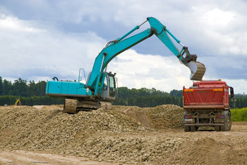 Fototapeta premium Excavator loading sand or rocks in lorry