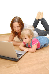 Mother and daughter with laptop on wooden  floor