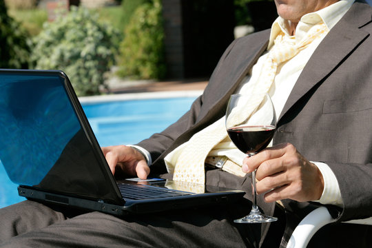 Businessman with laptop and glass of red wine