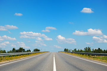 Fototapeta premium Empty countryside road leading straight to cloudy blue sky