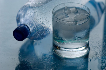 Water. Glass of water with an ice on a blue background