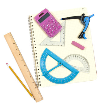 Mathematical instruments on spiral notebook on white