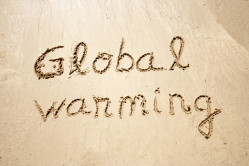 Global warming handwritten in sand for tourism