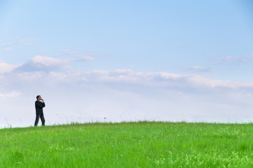 Manager steht auf der Wiese und gr&uuml;belt vorm Himmel