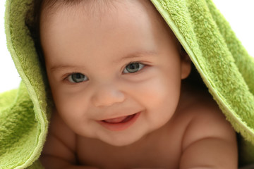 bébé souriant dans sa serviette verte