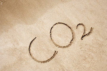 The word CO2 handwritten in sand on a beach