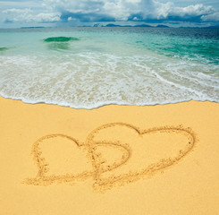 two hearts drawn in a sandy tropical beach
