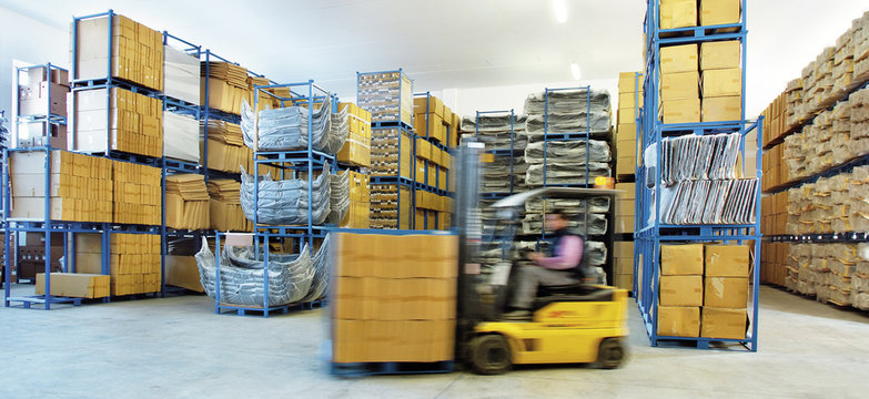 Automotive parts shipping warehouse. A moving forklift moves boxes inside the warehouse