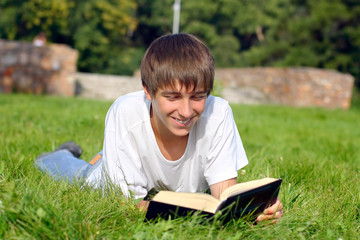The teenager reads the book on a summer meadow