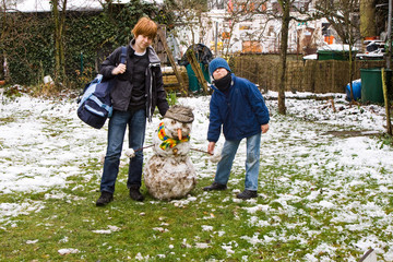 Kinder stehen neben ihrem tauenden Schneemann