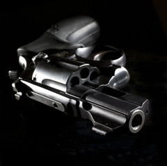 nighttime revolver that is staged on a black surface and angled toward the camera to see down the muzzle
