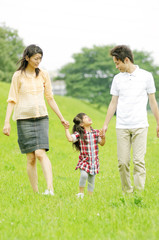 Fototapeta premium 両親と手をつないで歩く女の子