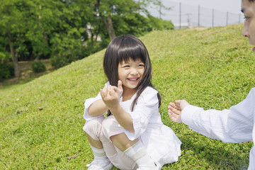 公園で娘の手をとろうとする父親