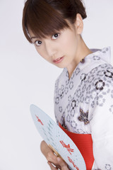 浴衣を着て団扇を持っている女性