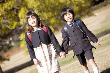 手をつないで歩く制服姿の小学生男女