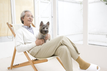 犬を抱いてイスに座るシニア男性
