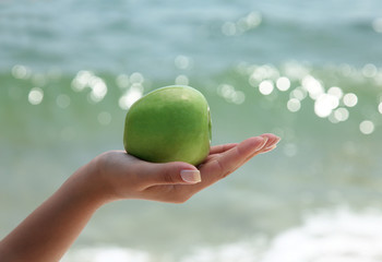 Woman`s hand holding a green apple