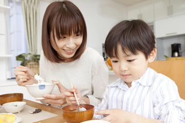 朝食時にご飯を食べる母親と息子