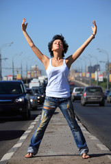 Fototapeta na wymiar girl stands on middle of road with rised hands