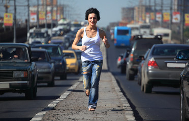 girl runs on highway middle in city