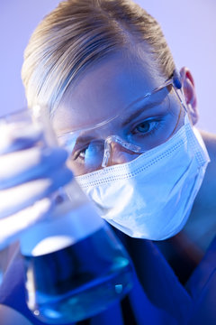 Female Scientist Doctor With Flask of Blue Liquid In Laboratory