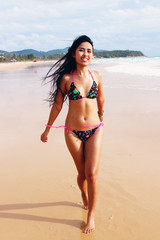 Beautiful Asian woman in a bright bikini at the beach.