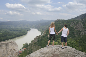 Jugendliches Paar blickt Hand in Hand in das Donautal der Wachau