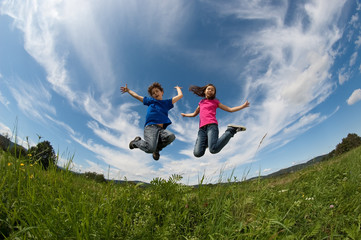 Kids running, jumping on green meadow