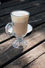 A glass of hot latte macchiato on a wooden table