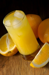 Oranges and orange juice in a glass on a dark background