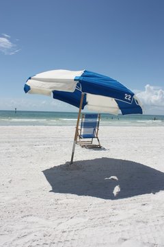Parasol et chaise longue sur sable blanc