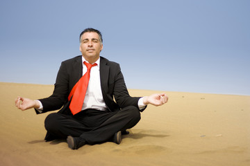 A business man relaxing and sit down on the sand of the desert