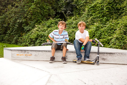 Kinder ruhen sich aus vom Roller und Skateboard fahren