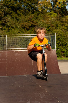 Kind mit Scooter, Roller, übt auf der Skatebahn Tricks
