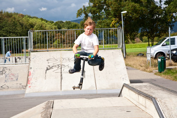 Kinder fahren Roller im Skate Park und üben Tricks