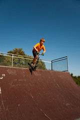 Kind mit Scooter, Roller, &uuml;bt auf der Skatebahn Tricks