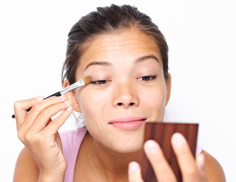 Mixed asian / caucasian woman putting makeup