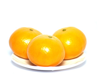 Three tangerines lie on a round white saucer