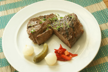 grilled pepper steak with some sour vegetables on a white plate