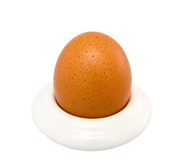 Brown egg in egg cup on a white, close-up