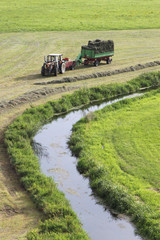 Traktor bei der Heuernte auf grünen Wiesen und Feldern