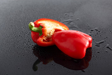 Paprika, rot, halbiert, auf schwarzem  Acryl