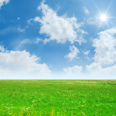 blue sky with sun and green field