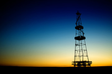 Oil rig silhouette over blue sky