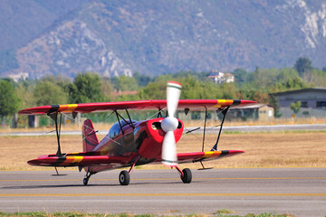 Red biplane taxying on the Brescia Montichiari airport taxyway