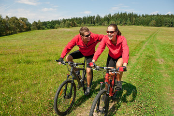 Fototapeta premium Sportive couple riding mountain bike in meadow