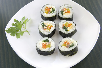 Six pieces of Korean sushi and a parsley leaf.