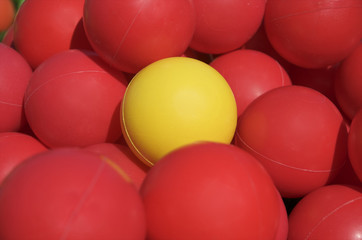 Tellow ball among red plastic balls