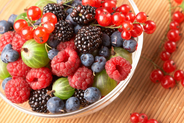 Fruit mix in the glass container, on a table from straw
